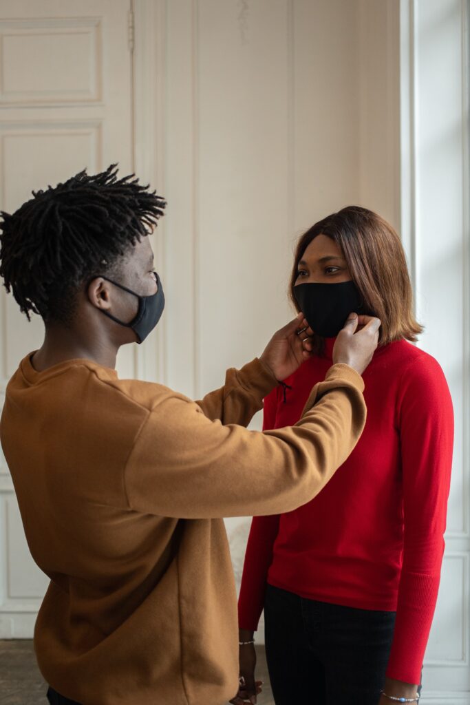 A man adjusts his female friend's mask
